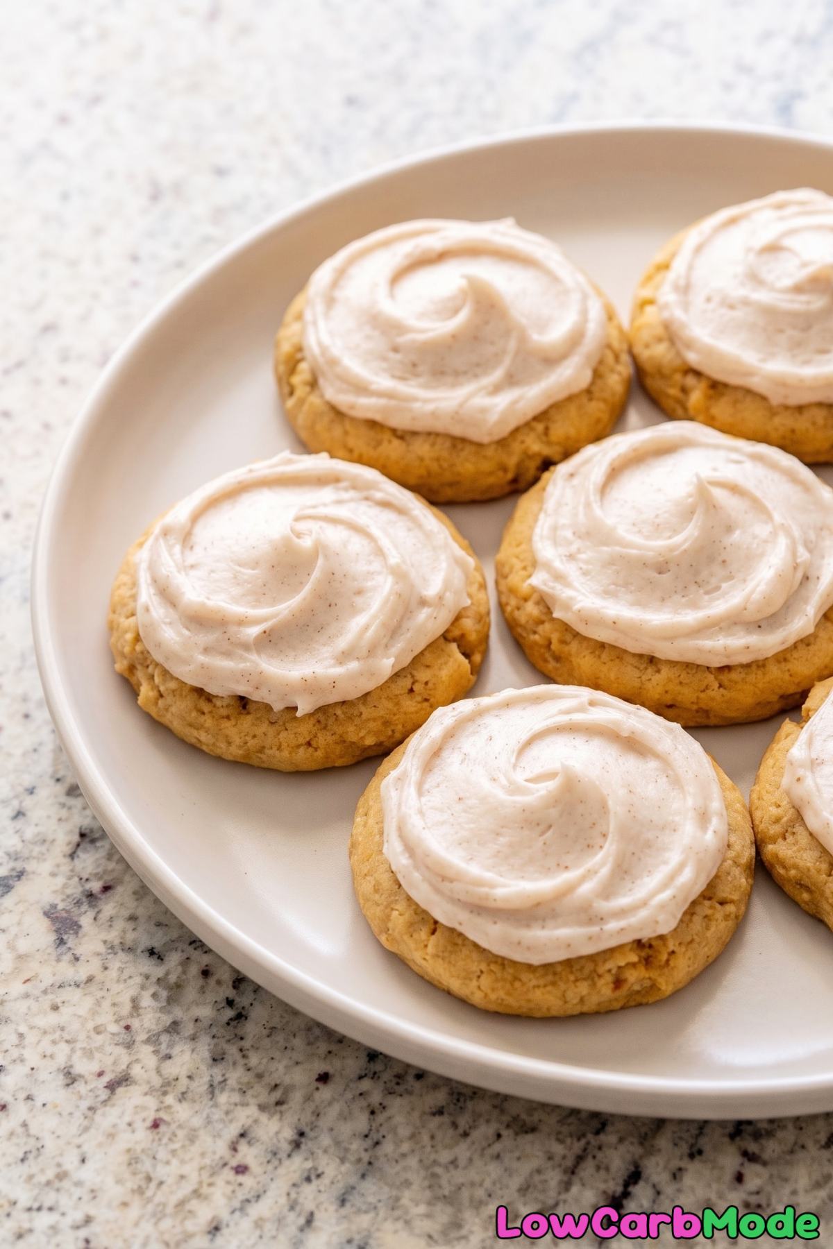 Frosted keto pumpkin cookies on a plate